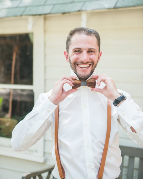 Groom smiling holding his wooden bow tie